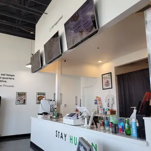 a restaurant counter with tvs on the wall