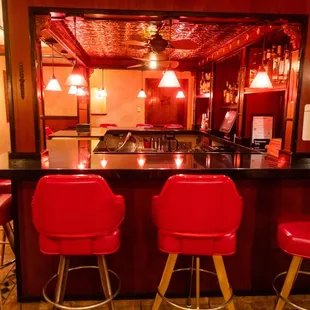 a bar with red chairs