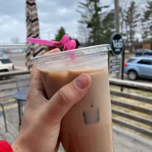 a hand holding a cup of iced coffee