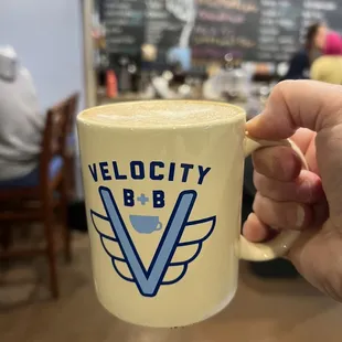 Hot latte in a real mug with menu in the background.