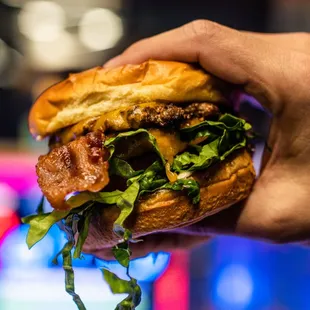 a hand holding a hamburger
