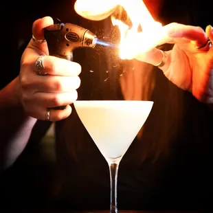 a woman holding a lighter and a cocktail glass