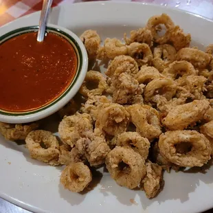 a plate of fried calamails and a bowl of tomato sauce