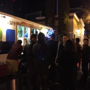 a line of people waiting in line at a food truck