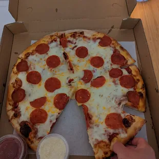 a hand reaching for a slice of pepperoni pizza