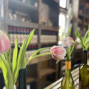 a row of wine bottles with tulips in them