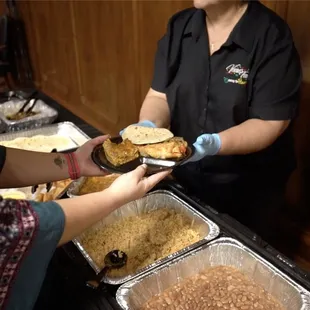 Ventura&apos;s Tamales serving someone at a catered event.