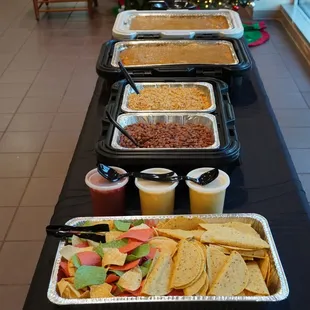 Catered meal with chips and queso with rice and beans and enchilada casserole.