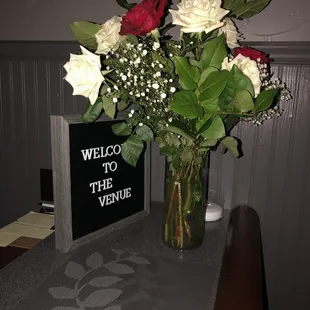 a vase of flowers on a table with a welcome sign