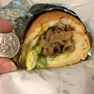 12” Cheesesteak sub, unaltered, next to a quarter to demonstrate amount of filings when received.