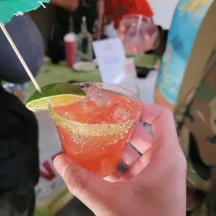 a hand holding a margarita with a lime wedge