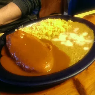 Chile relleno covered in mole sauce, beans and rice. (B)