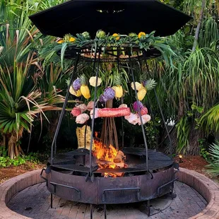 Lunch meat with fruits and veggies hanging above the fire.