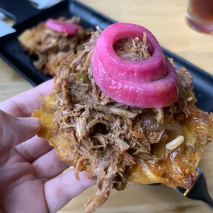 a hand holding a pulled pork sandwich