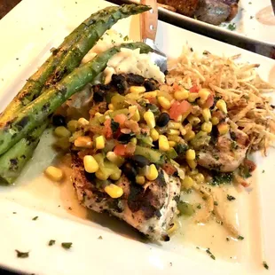 Verf's chicken garnished with hatch chiles, roasted corn, black beans and cilantro, and served with mashed potatoes and grilled asparagus.