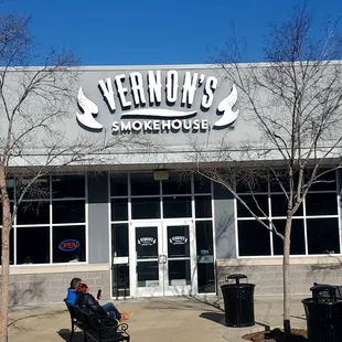 a man sitting on a bench in front of a restaurant