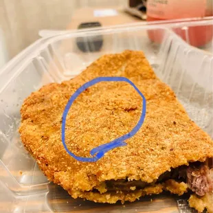 a piece of breaded meat in a plastic container