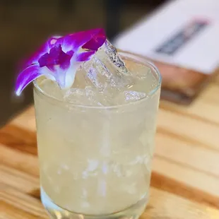 a cocktail with a purple flower