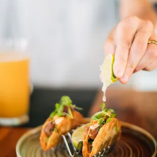 a person holding a slice of lime over a plate of food