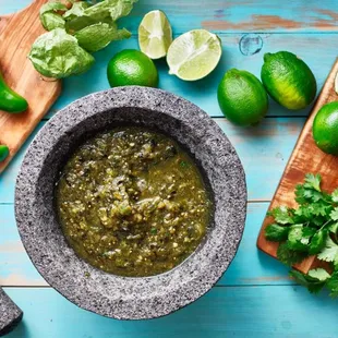 a mortar filled with salsa and limes