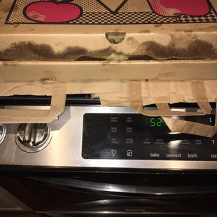 a box of pizza sitting on top of a stove