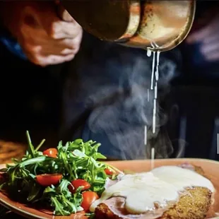 a person pouring gravy over a plate of food