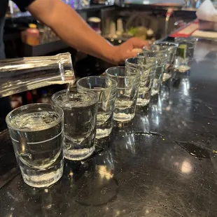 a line of shot glasses lined up on a bar