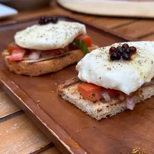 two open sandwiches on a wooden tray