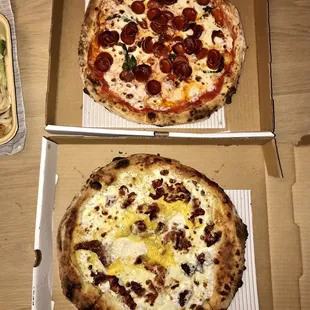 two pizzas in boxes on a table