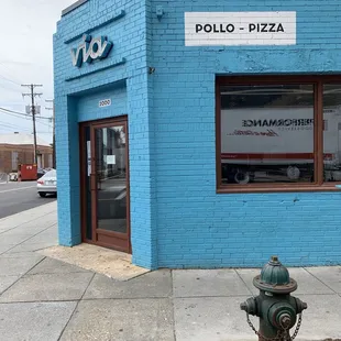 a fire hydrant in front of a blue brick building