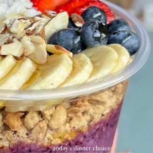 ows a hand holding a bowl of fruit and oatmeal