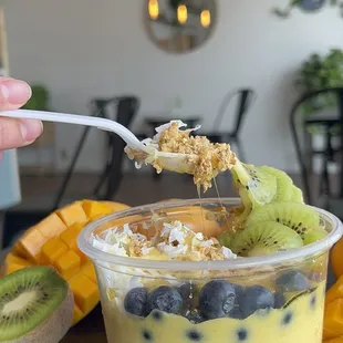 ows a hand holding a spoon full of fruit