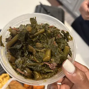 a person holding a bowl of greens