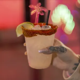 a hand holding a glass of margarita