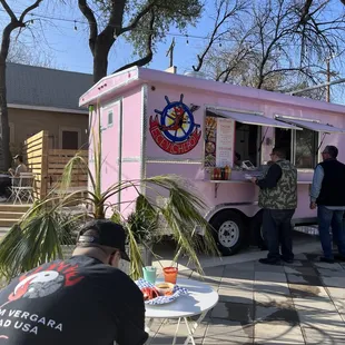 a pink food truck with people standing outside