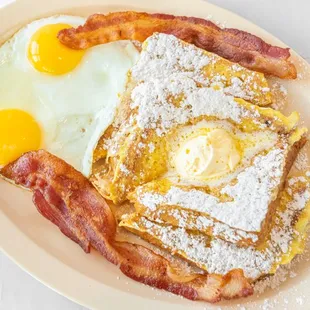 Irresistible French Toast Combo: four cinnamon powdered triangles, two XL eggs and choice of two crispy bacon strips or two savory sausages.