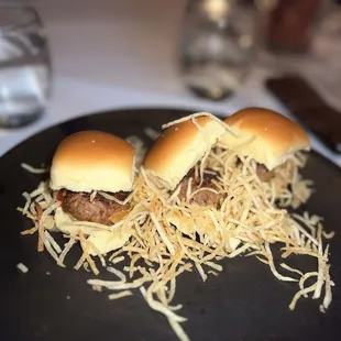a plate of sliders with shredded cheese
