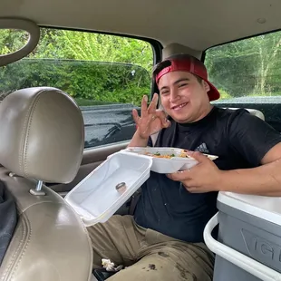 a man sitting in the back of a car eating a hot dog