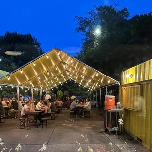 people sitting at tables under a canopy