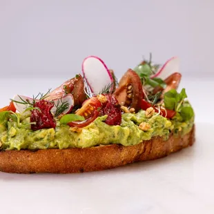 a sandwich with avocado, bacon, and radishes