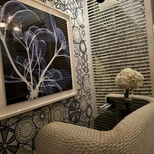 a living room with a white chair and a black and white wallpaper