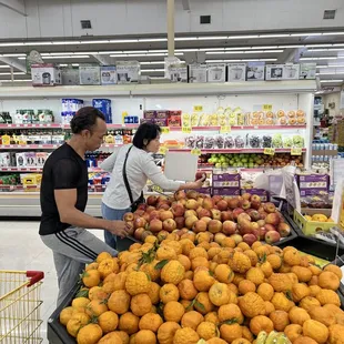 a man and a woman shopping for fruit