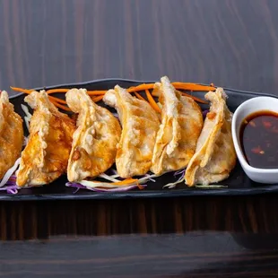 a plate of dumplings with dipping sauce