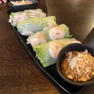 a plate of rice rolls and a bowl of dipping sauce