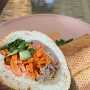 a half eaten sandwich on a pink plate