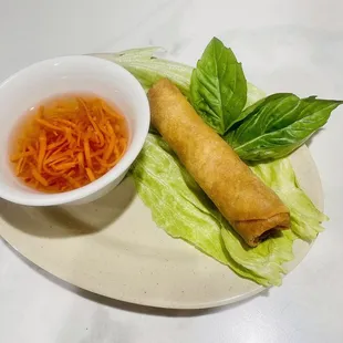 a vegetable spring roll and a bowl of dipping sauce