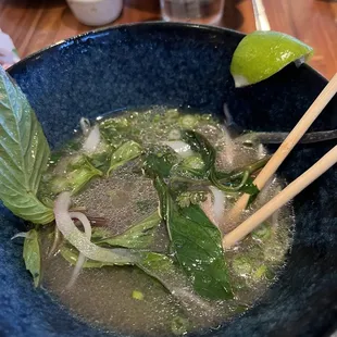 a bowl of soup with chopsticks