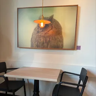 a table with two chairs and a picture of an owl on the wall