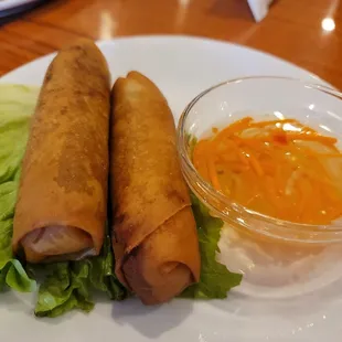 a plate of fried spring rolls and a bowl of dipping sauce