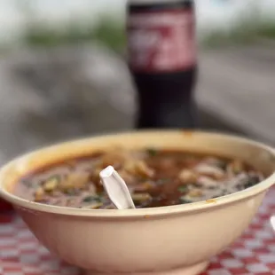 a bowl of soup and a bottle of soda